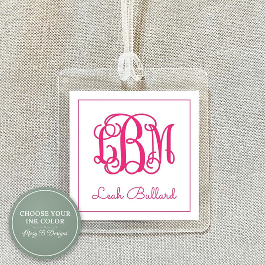 a clear square tag with a pink monogram and the name "Leah Ballard" printed on it.