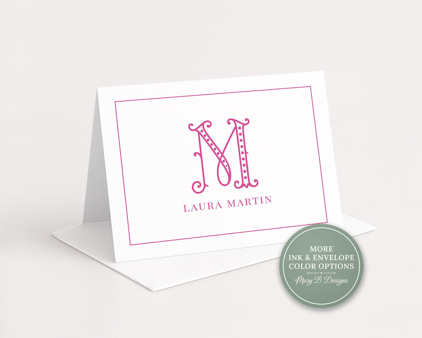 A white greeting card with a pink monogram logo and the name 'LURA MARTIN' printed on it.
