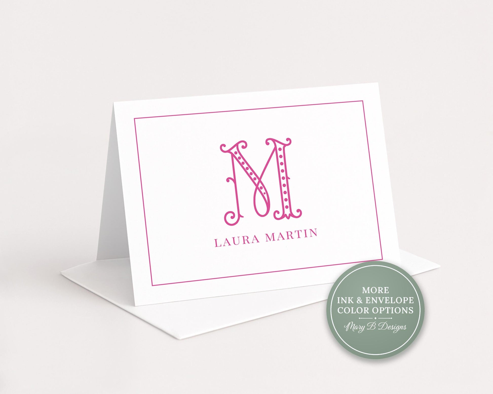 A white greeting card with a pink monogram logo and the name 'LURA MARTIN' printed on it.