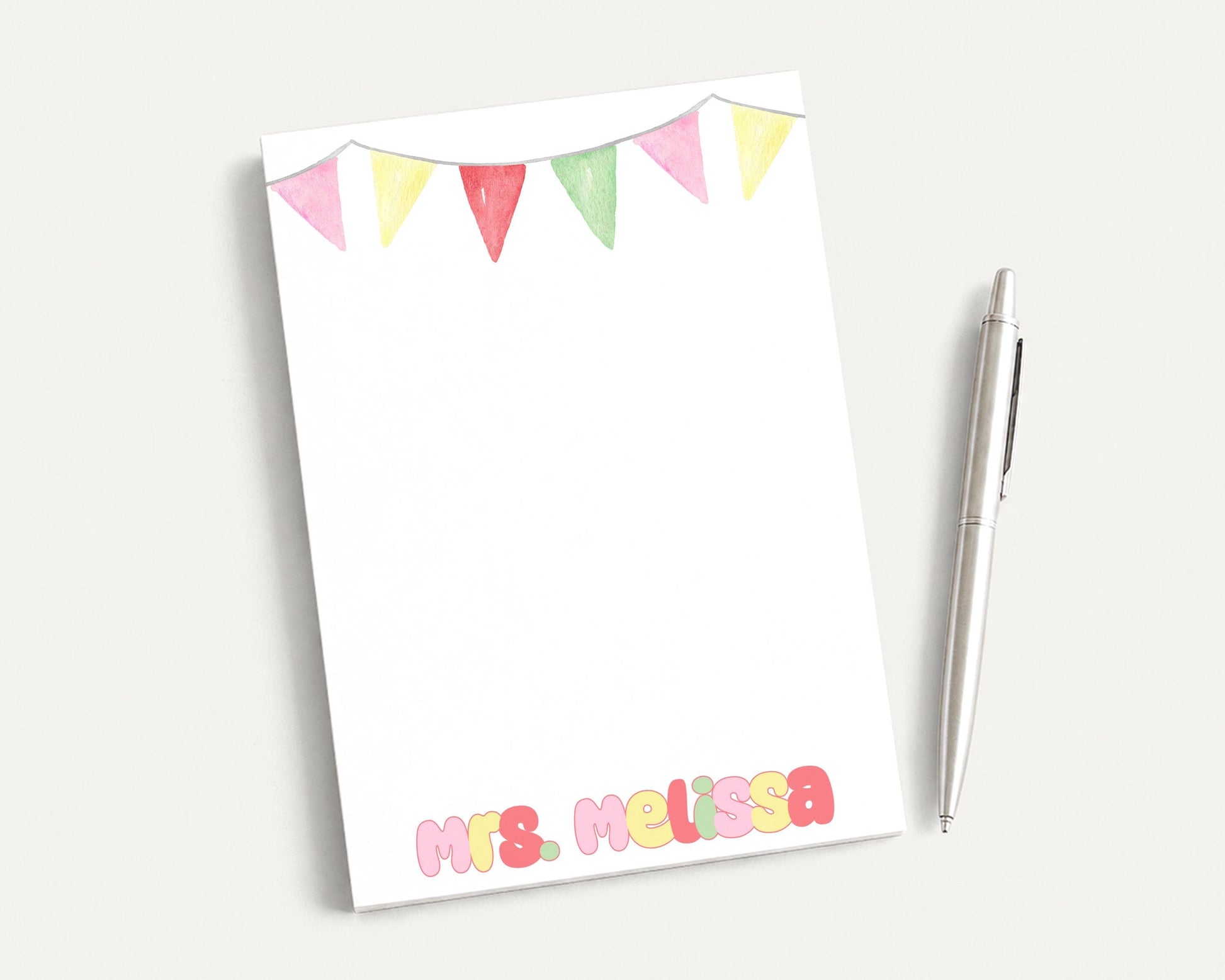 a blank white notepad with a decorative border and a name written on it, along with a pen placed next to it.