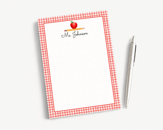 A red and white checkered notepad with a pencil and a pen on a white background.