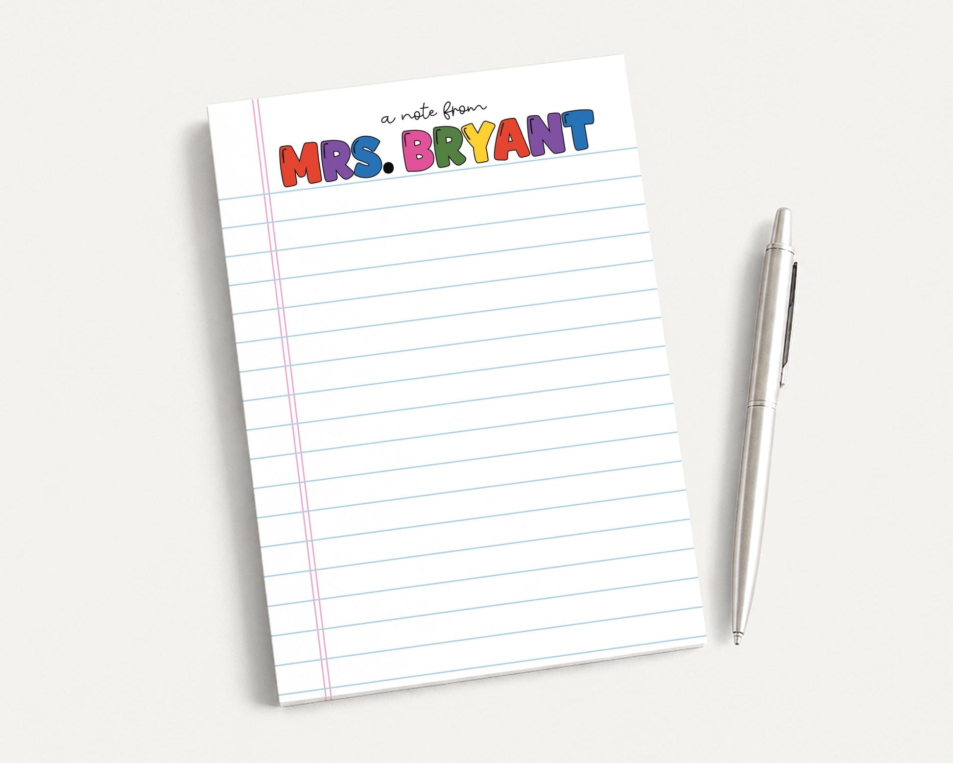 A lined notepad with the name "Mrs. Bryant" written on it, along with a pen, is placed on a white surface.