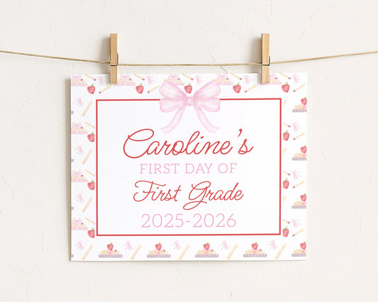 A white sign with a pink bow and the text "Caroline's FIRST DAY OF FIRST GRADE" is hanging on a string.
