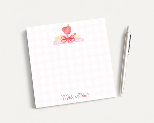 A white notepad with a pink bow and a pen on a white background.