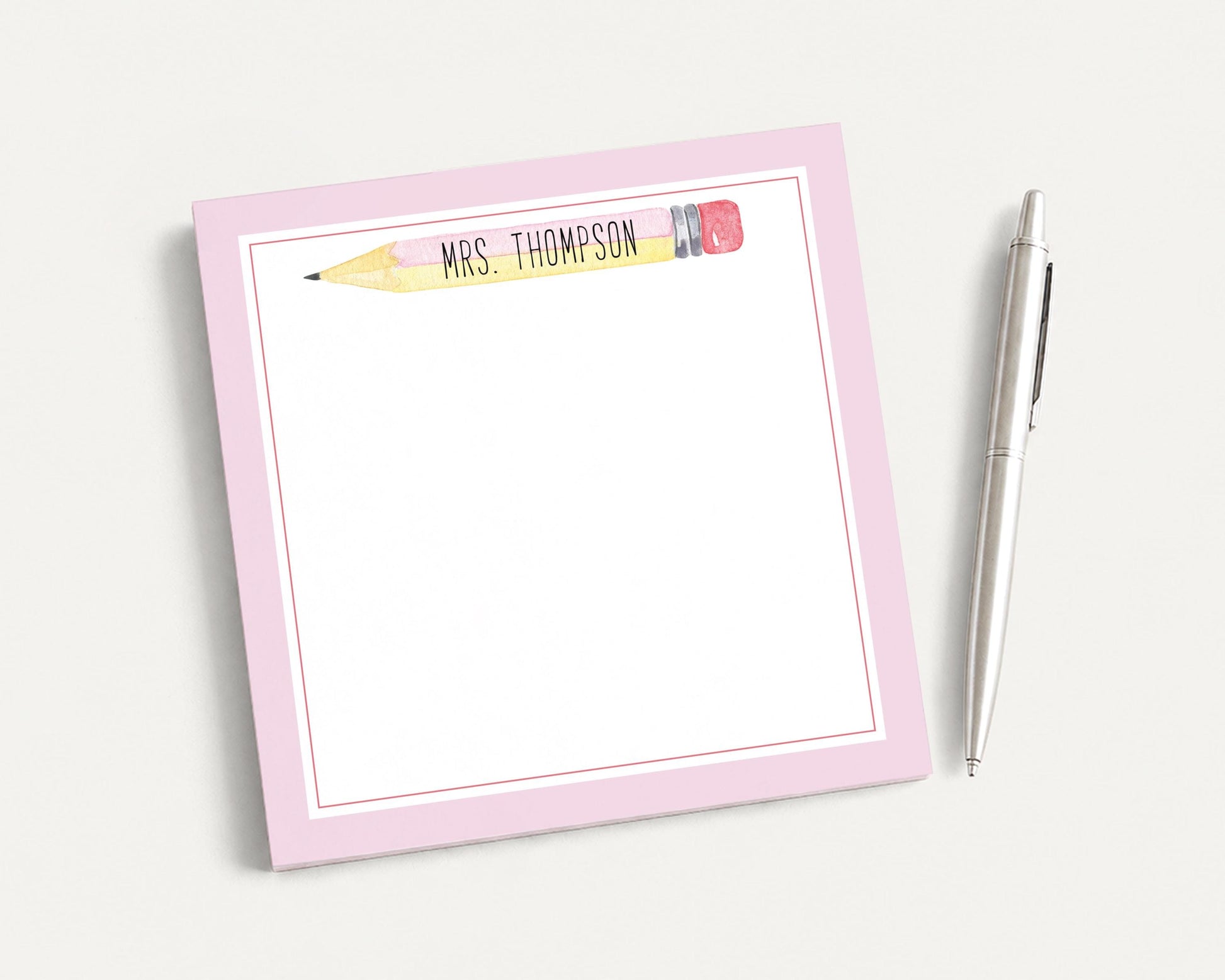 A pink sticky note pad with a personalized name and a pen on a white background.