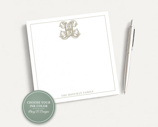 A white notepad with a monogrammed initial and a pen on a plain white background.
