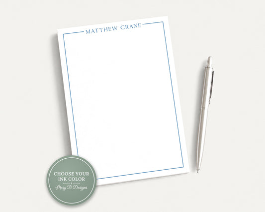 A blank white notepad with the name 'MATTHEW CRANE' written on it, accompanied by a silver pen on a plain white background.