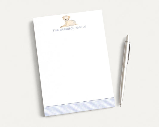 a white notepad with a watercolor illustration of a dog on it, and a pen is placed next to it on a white surface.