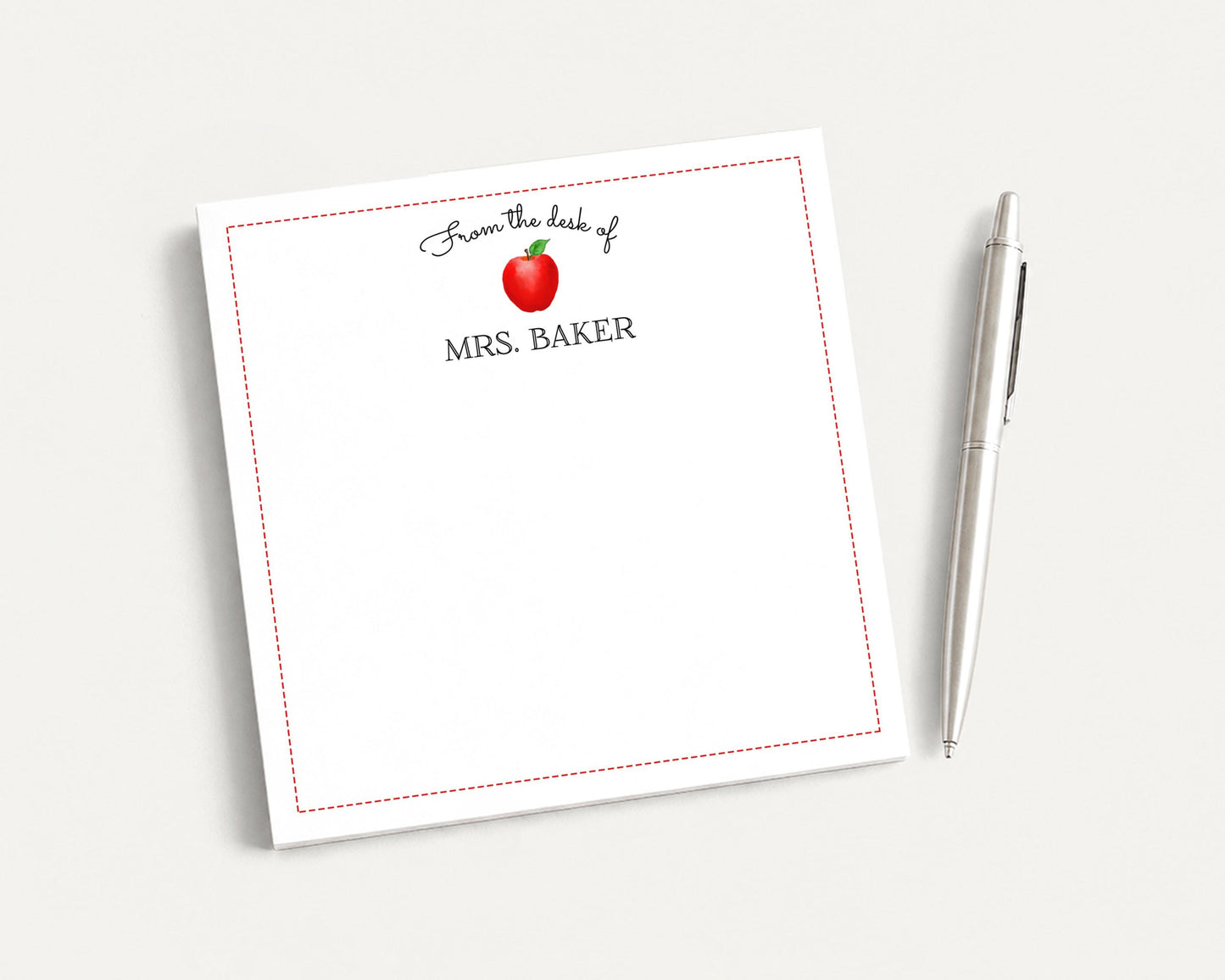 A white notepad with a red border and a pen on a white surface.