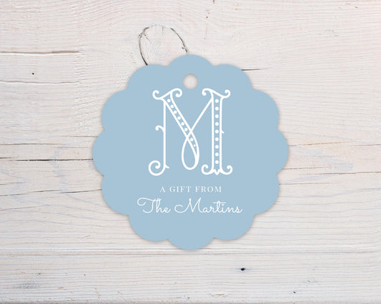 A light blue scalloped-edge tag with a white letter "M" and text that reads "A GIFT FROM The Martins".