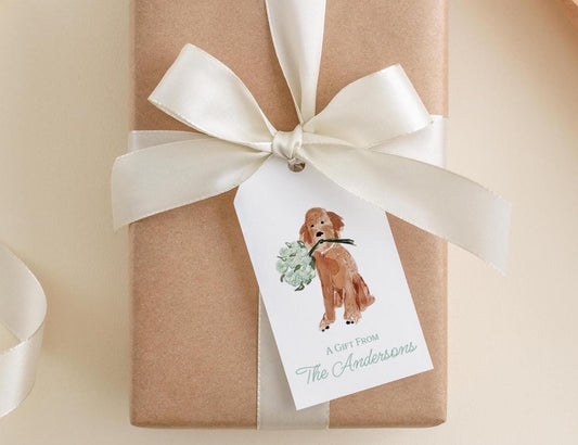A brown gift box with a white ribbon and a tag featuring a picture of a dog holding a green plant.