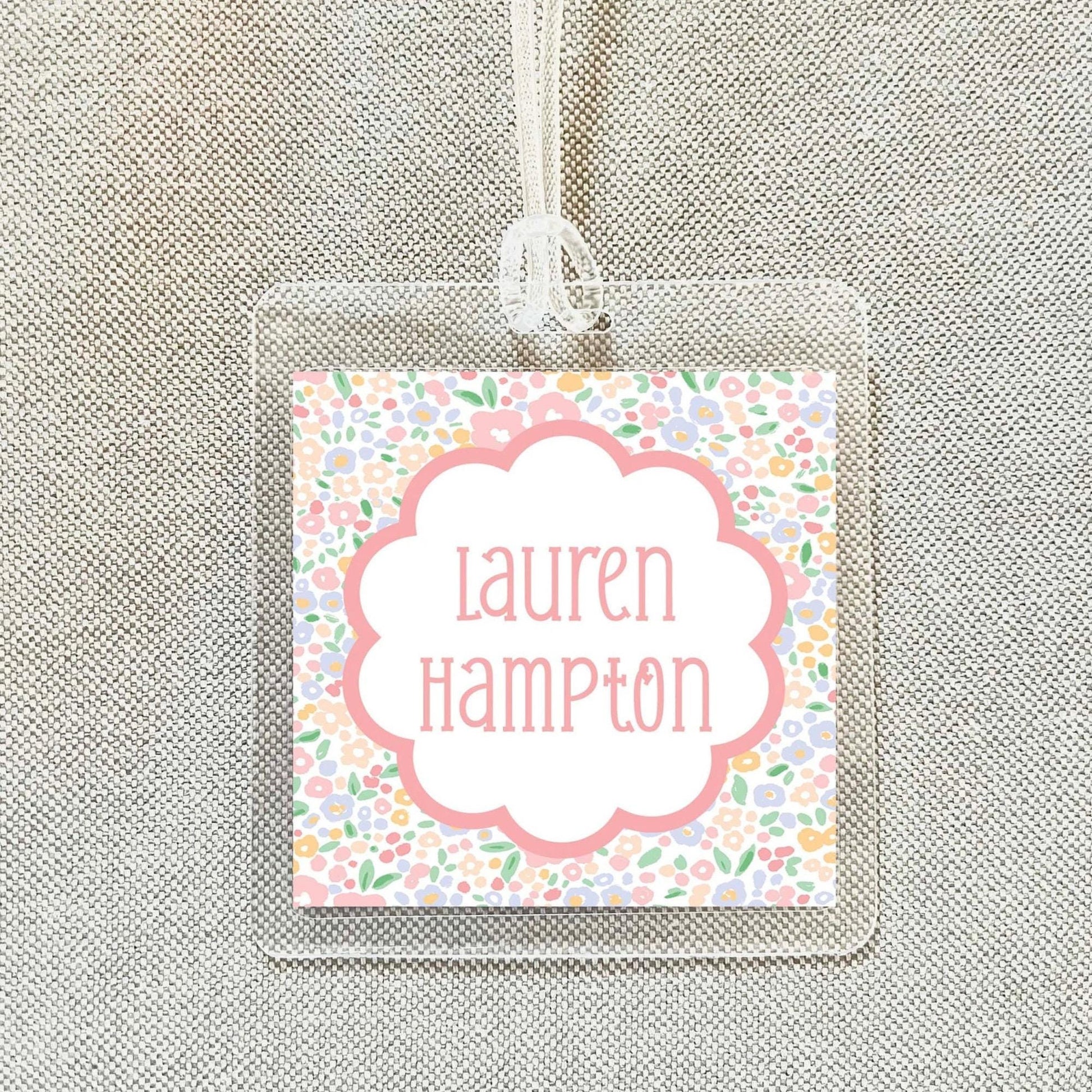 A clear plastic name tag with a floral design and the name "Lauren Hampton" printed on it.