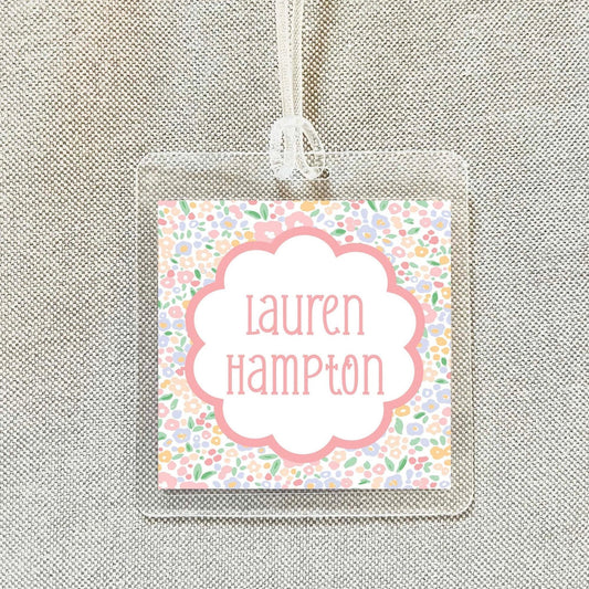 A clear plastic name tag with a floral design and the name "Lauren Hampton" printed on it.
