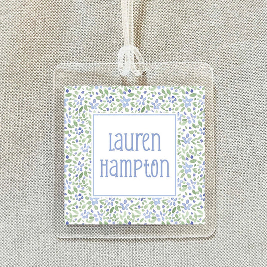 A clear name tag with a floral pattern and the name "Lauren Hampton" printed on it.