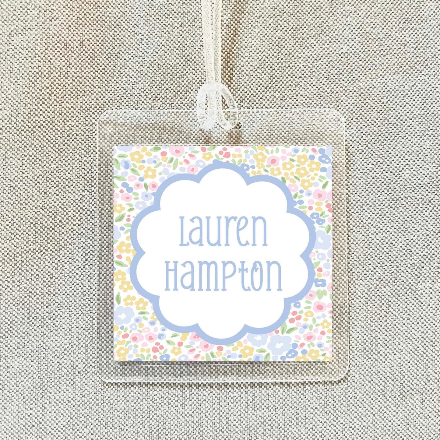 A clear plastic name tag with a floral design and the name "Lauren Hampton" printed on it.