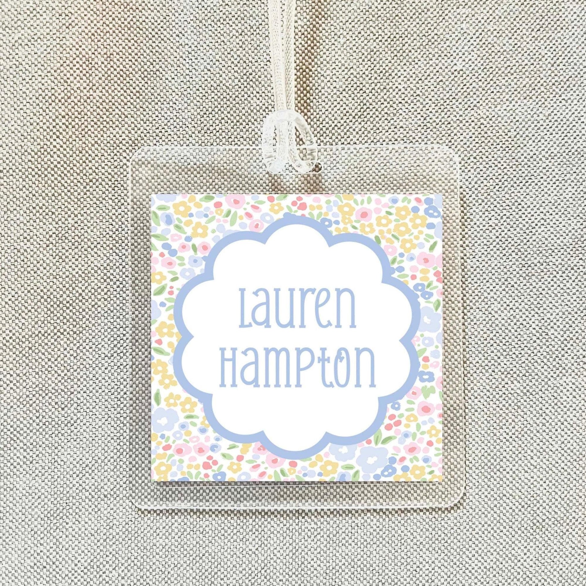 A clear plastic name tag with a floral design and the name "Lauren Hampton" printed on it.