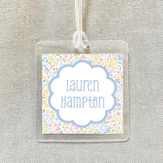 A clear plastic name tag with a floral design and the name "Lauren Hampton" printed on it.