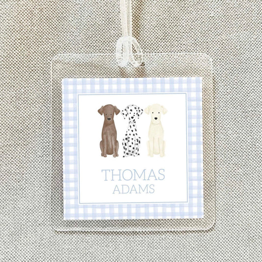 A personalized name tag with a picture of three dogs, including a Dalmatian, a brown dog, and a white dog, along with the name 'Thomas Adams'.