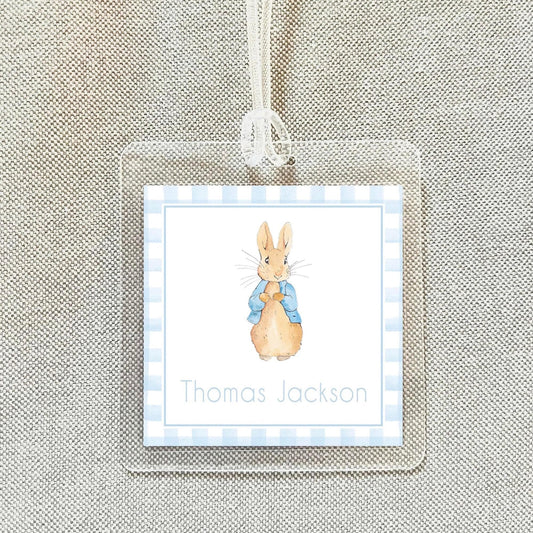 A clear name tag with a picture of a rabbit wearing a blue coat and the name "Thomas Jackson" printed on it.