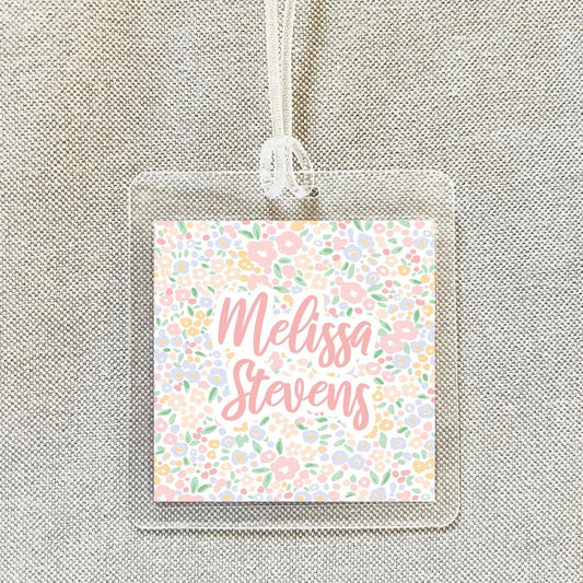 A clear plastic name tag with a floral design and the name "Melissa Stevens" printed on it.