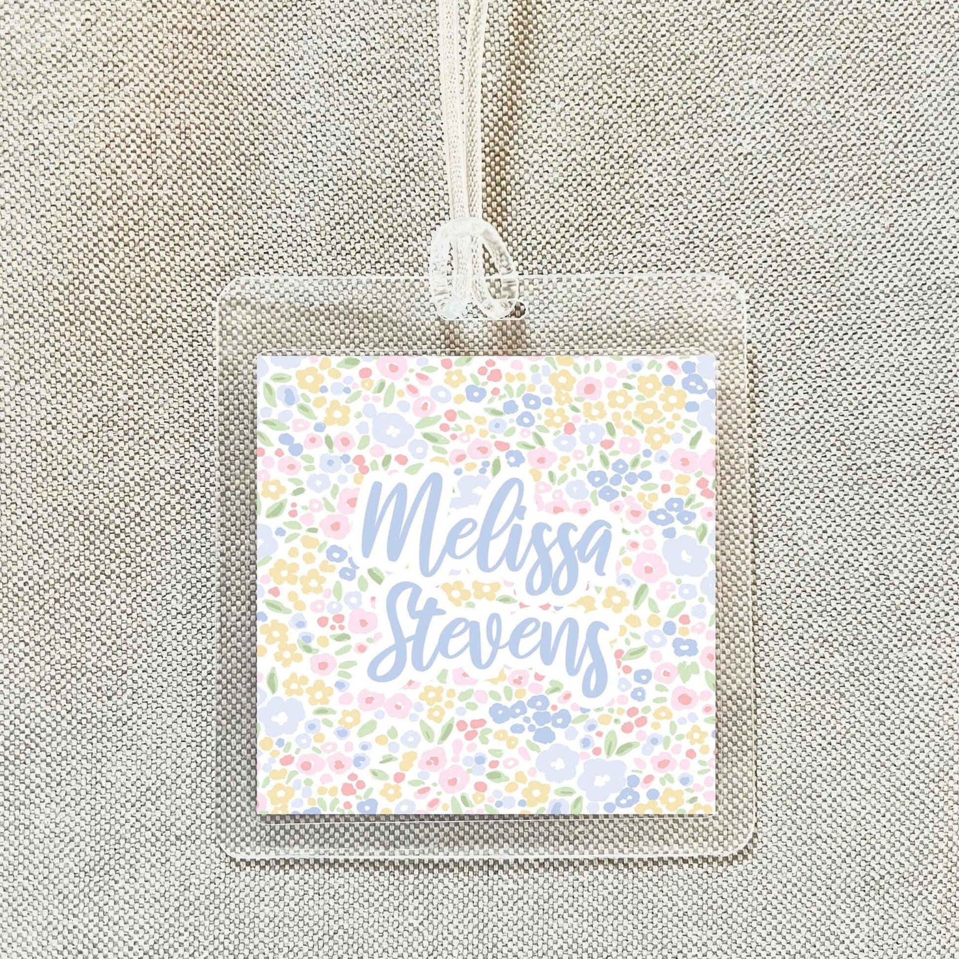 A clear plastic name tag with a floral design and the name "Melissa Stevens" printed on it.