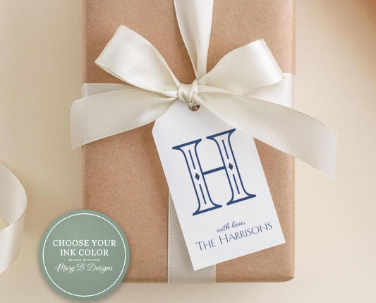 A brown gift box with a white ribbon and a personalized tag attached to it.