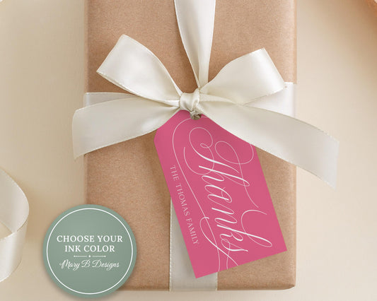 A gift box wrapped in brown paper with a pink ribbon and a white bow, along with a pink tag that says "Thanks" in cursive script.