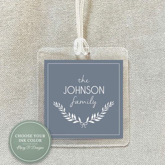 A clear plastic tag with a gray background and white text, hanging from a string.
