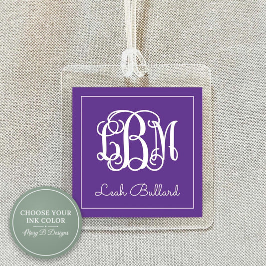 A purple square tag with a monogrammed initials and the name "Leah Bullard" printed on it, hanging from a string.