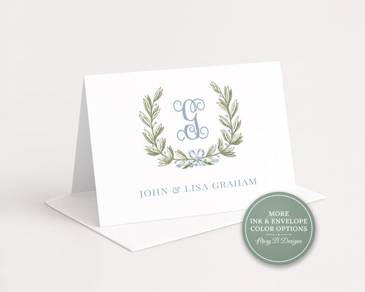 A white greeting card with a monogrammed logo and text, placed on a white surface.