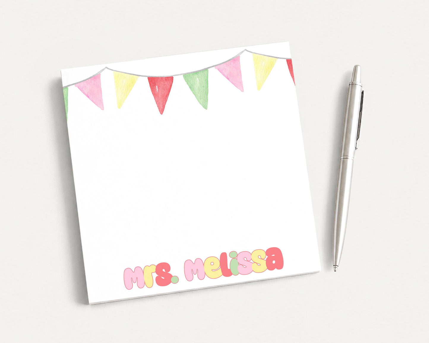 A white notepad with a decorative border and a pen on a plain white background.