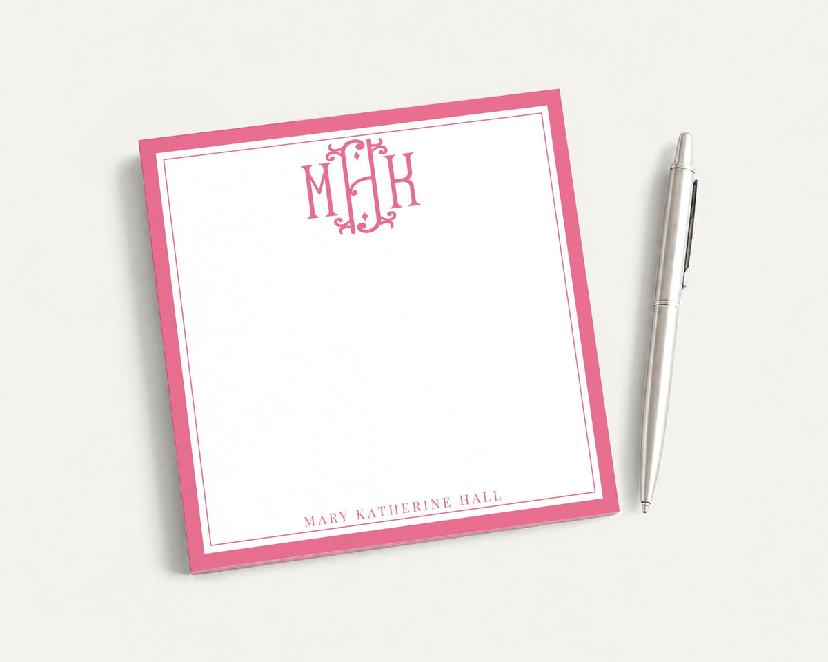 A pink-bordered notepad with a pen next to it, both resting on a white surface. __etsy:8253397989