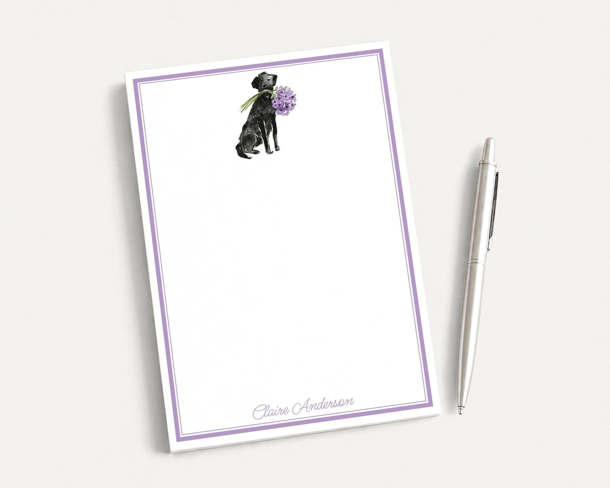 a blank notepad with a purple border, and a pen is placed next to it on a white surface.
