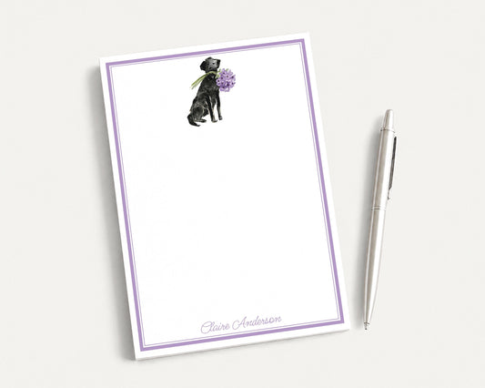 a blank notepad with a purple border, and a pen is placed next to it on a white surface.