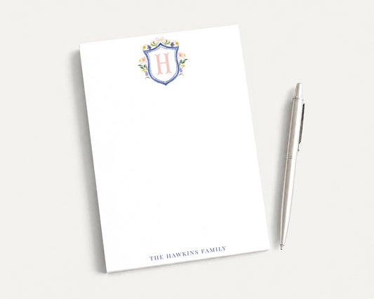 a blank white notepad with a pen next to it, both placed on a white surface.